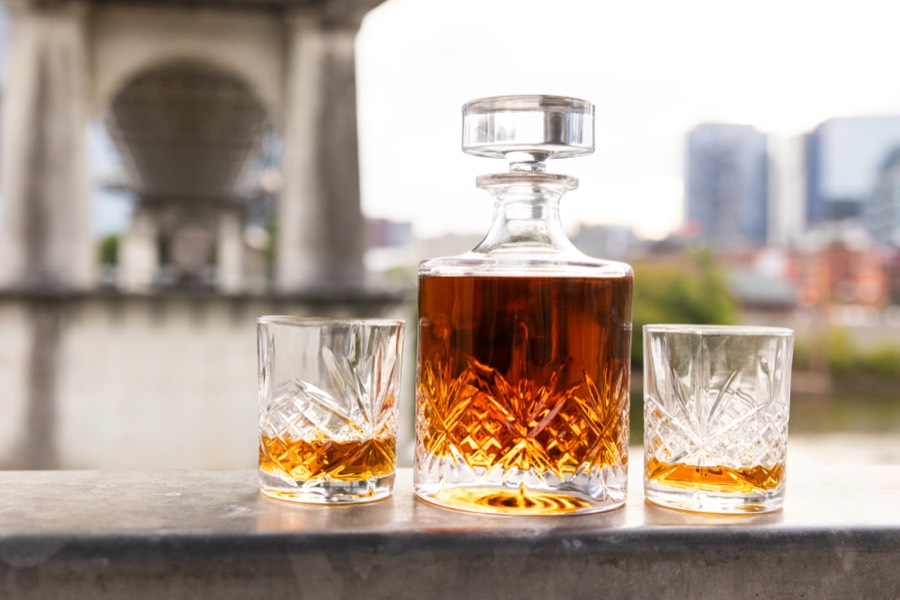 A crystal decanter of bourbon with two glasses by the river